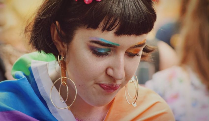 A woman wearing a rainbow colored dress and hoop earrings.