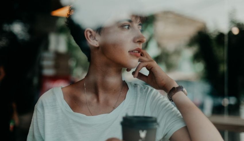 A woman looking out of a window with a cup of coffee.