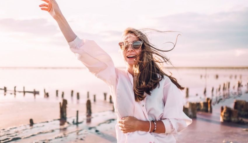 A woman is standing on a beach with her arms outstretched.