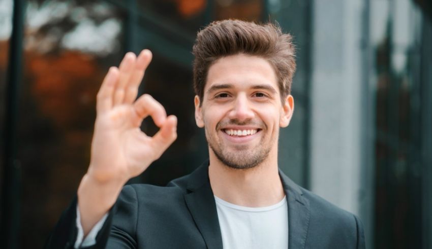 A man in a suit is making the ok sign.