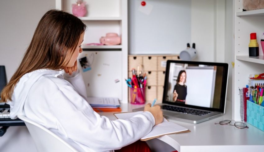 A girl sitting at a desk with a laptop in front of her.