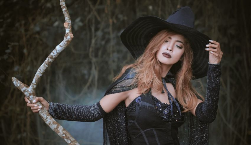 A woman dressed as a witch holding a stick.