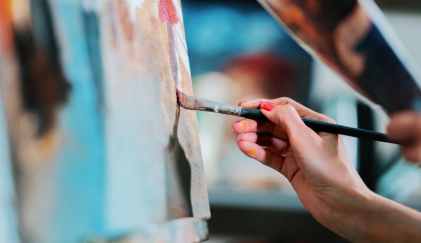 A woman is painting with a brush on an easel.