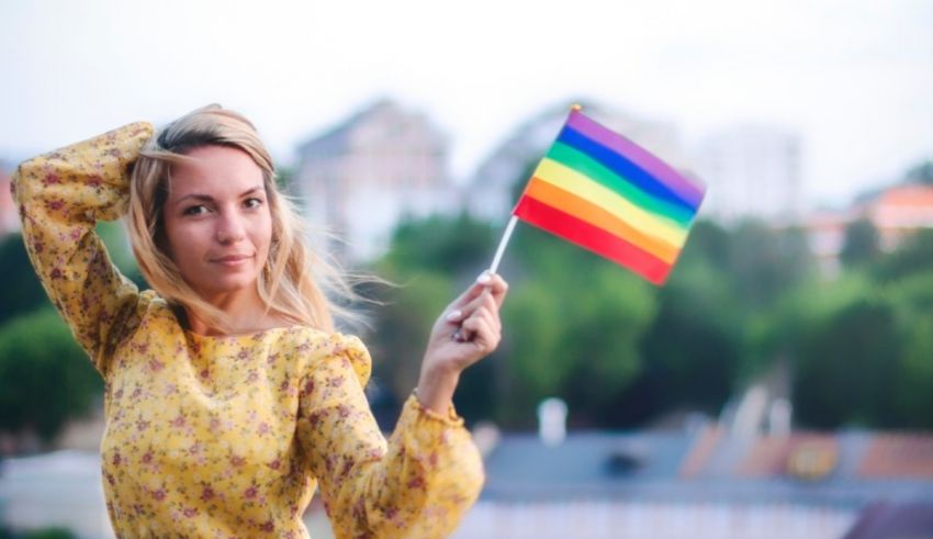 A woman holding a rainbow flag in front of a city.