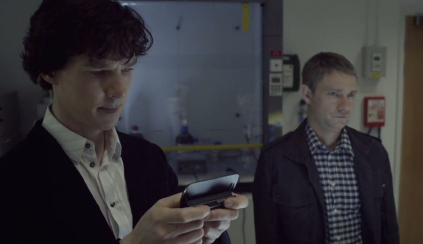 Two men standing next to each other looking at a cell phone.
