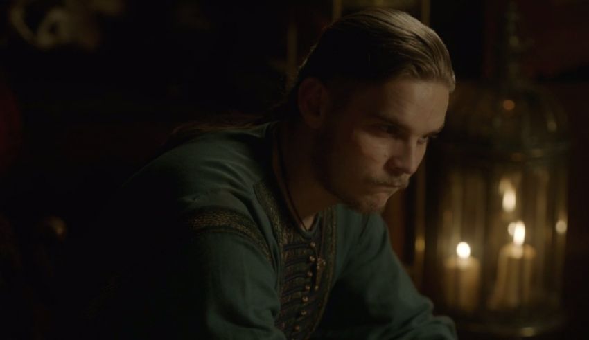 A man in a green shirt is sitting at a table with candles.