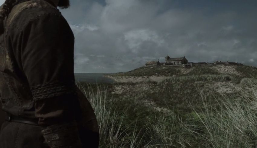 A man is standing on a hill overlooking a castle.