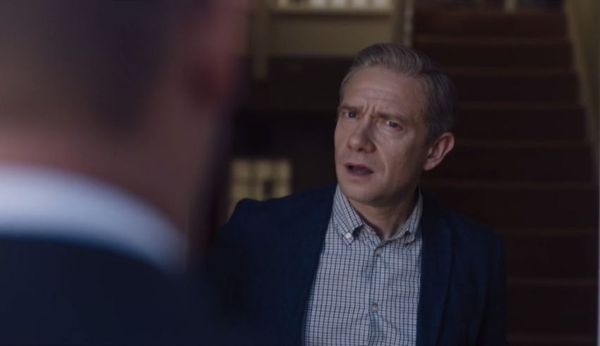 A man in a suit is standing next to a staircase.