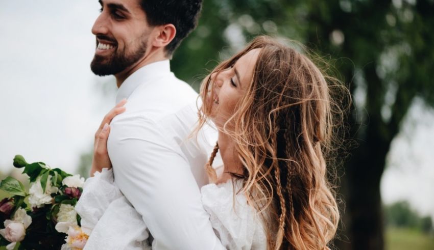 A bride and groom hugging in a field.