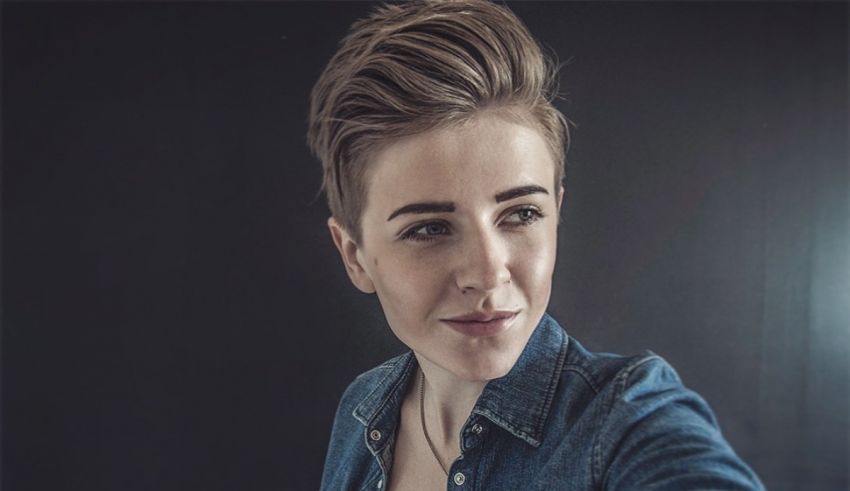 A woman in a denim shirt is taking a selfie.