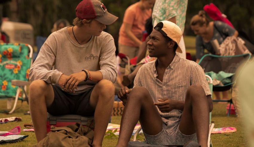 Two men sitting on lawn chairs talking to each other.