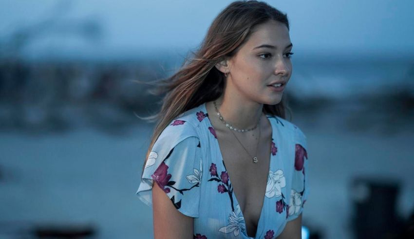 A woman in a floral dress standing on the beach.