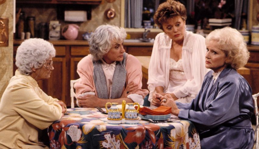 A group of women sitting around a table in a kitchen.