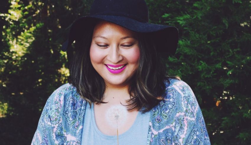 A woman wearing a hat and pink lipstick.