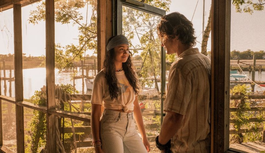 A man and woman standing in front of a window looking at the water.