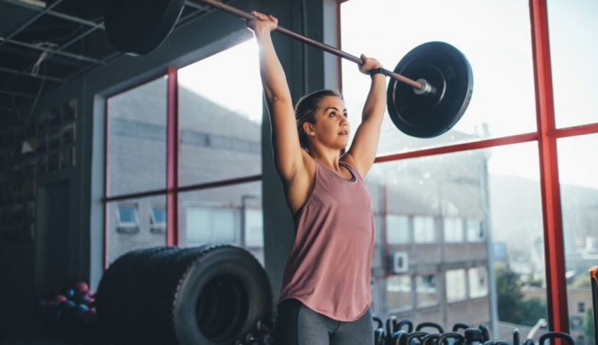 A woman lifting a barbell in a gym.