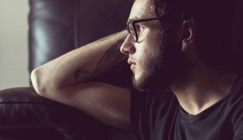 A man wearing glasses is sitting on a couch.