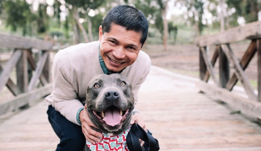 A man posing with his dog on a bridge.