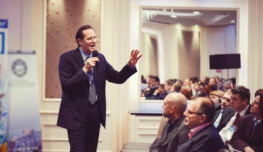 A man speaking into a microphone in front of an audience.