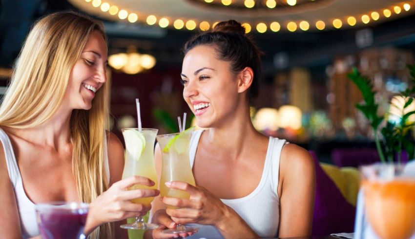 Two women drinking cocktails at a bar.