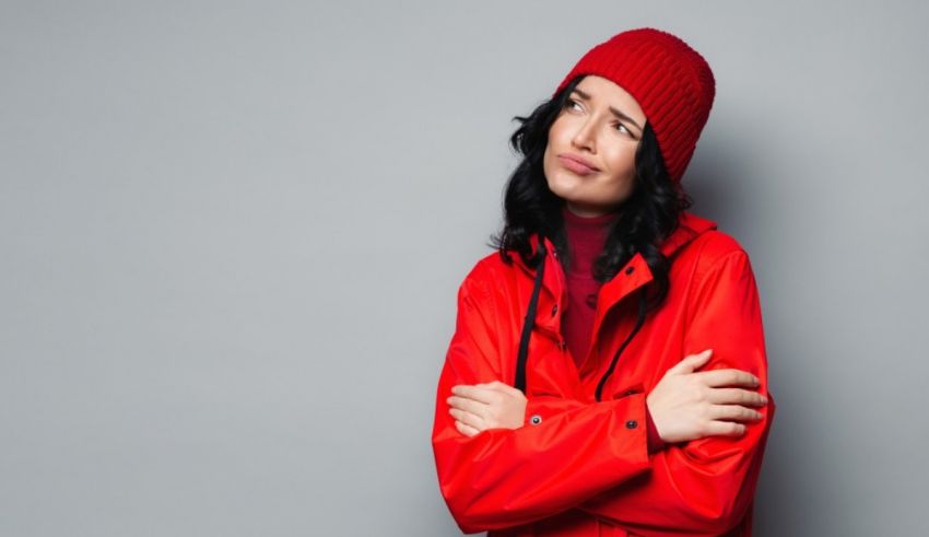 A woman in a red coat with her arms crossed.