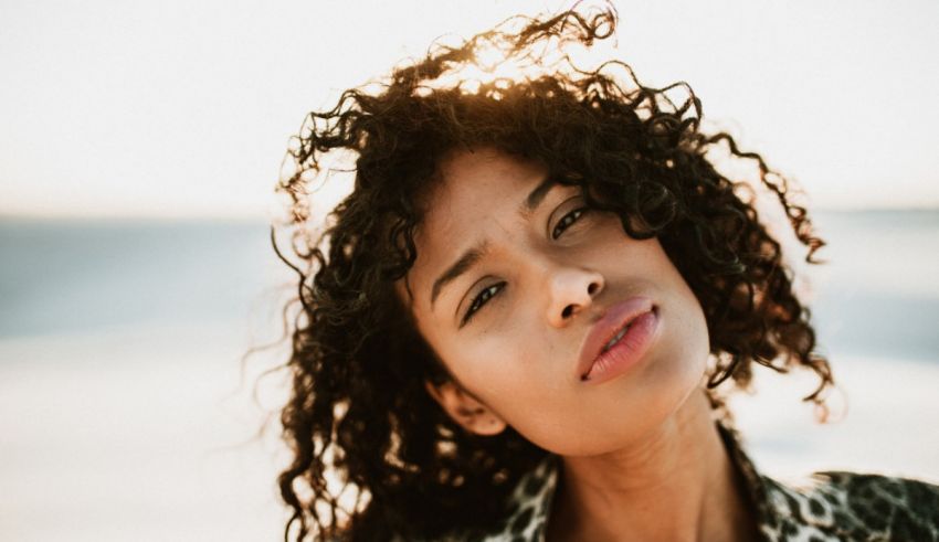 A woman with curly hair looking up at the sun.