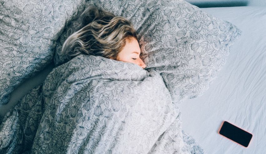 A woman sleeping in bed with a cell phone.