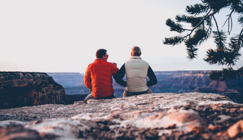 Two men sitting on a cliff overlooking the grand canyon.
