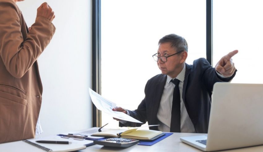 A man and woman in a business meeting pointing at each other.
