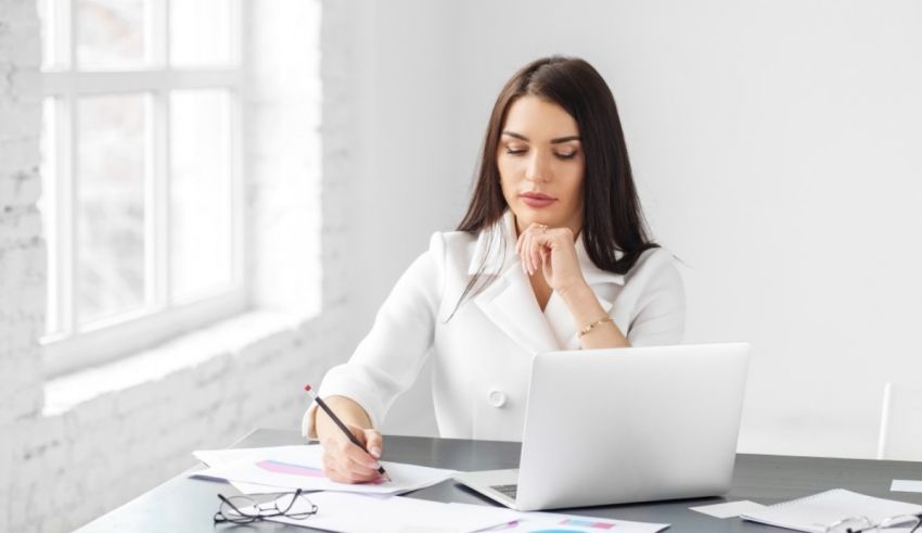 A business woman sitting at a desk with a laptop and papers.