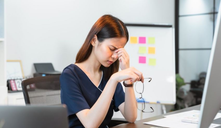 A woman is sitting at her desk with her eyes closed.
