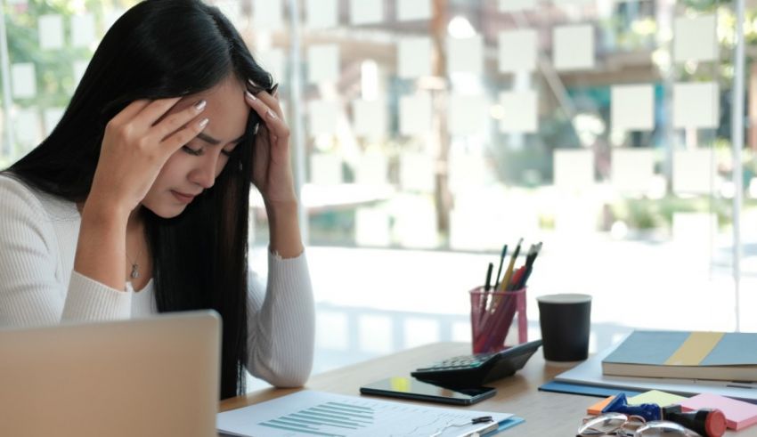 A woman is sitting at a desk with her head on her head.
