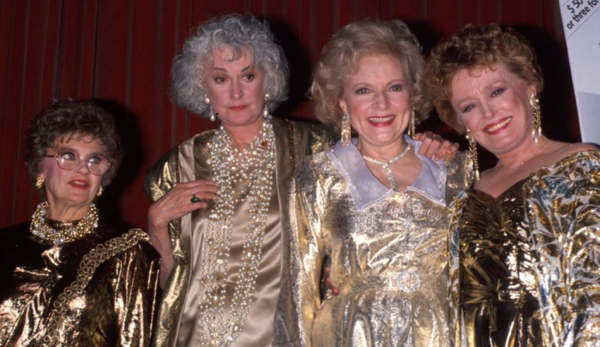 Four women in gold dresses posing for a picture.