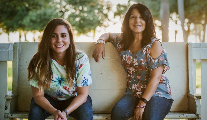 Two women sitting on a bench in a park.