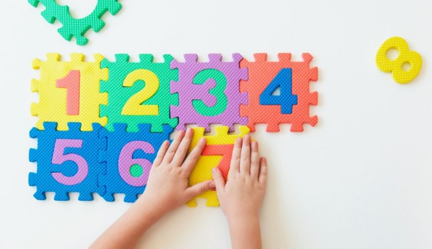 A child's hands are holding colorful puzzle pieces on a white background.