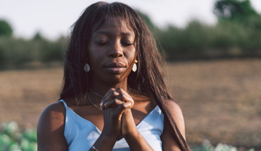 A black woman praying in a field.