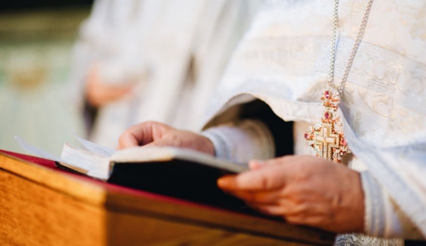 A priest is holding a book in front of him.