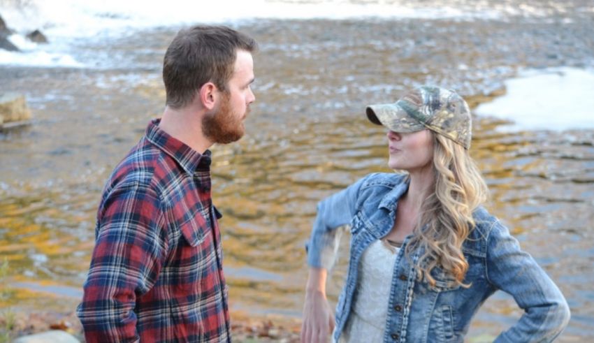 A man and woman standing next to a river.