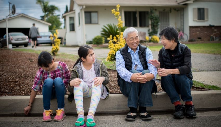 A family sits on the curb talking to each other.