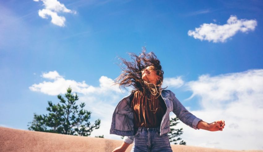 A woman is dancing in the desert with her hair blowing in the wind.