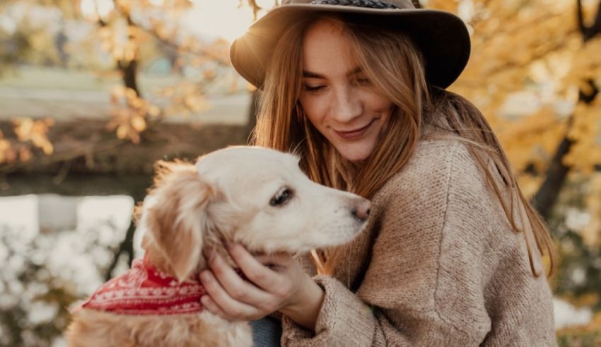 A woman holding a dog in autumn.