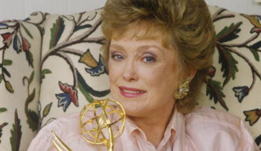 A woman sitting on a couch holding an emmy award.