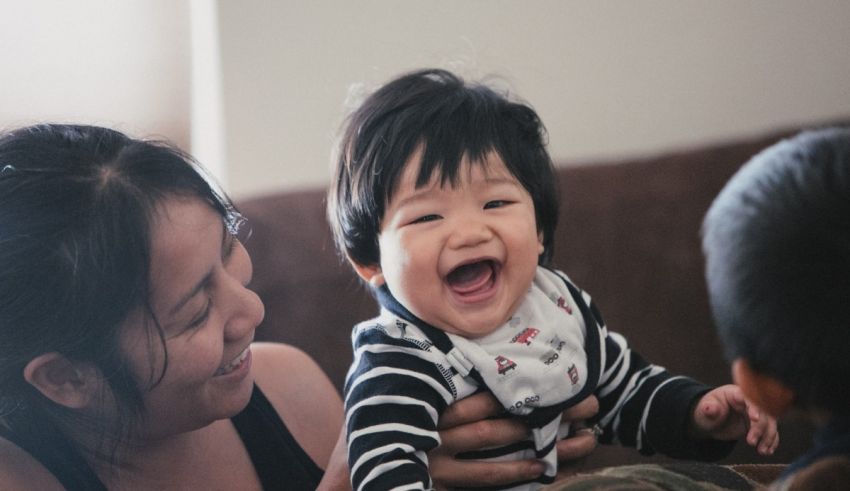 A woman laughs while holding a baby.