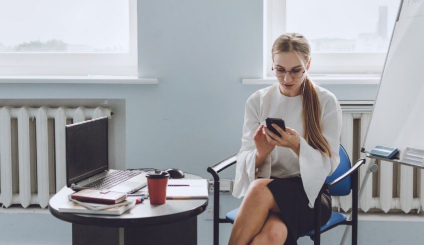 A woman sitting in a chair and using a cell phone.