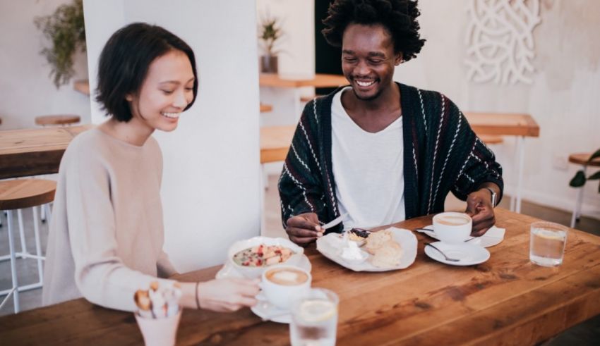 A man and woman are sitting at a table and drinking coffee.