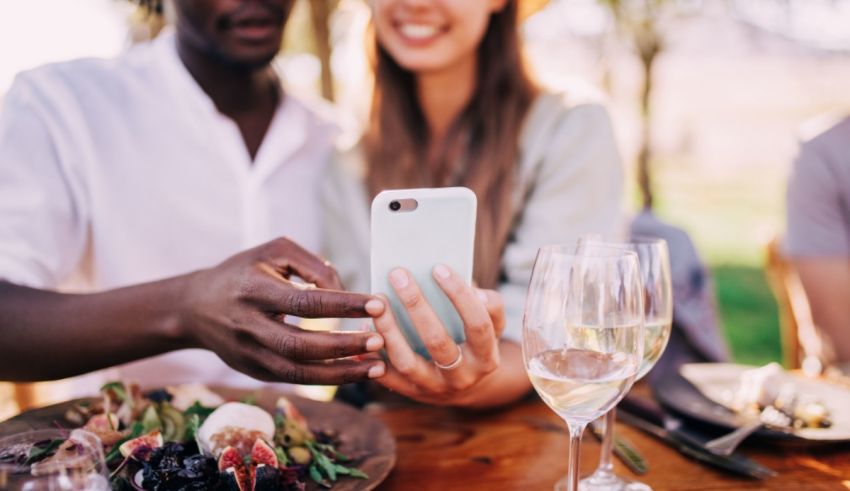A group of people at a table taking a selfie with a cell phone.