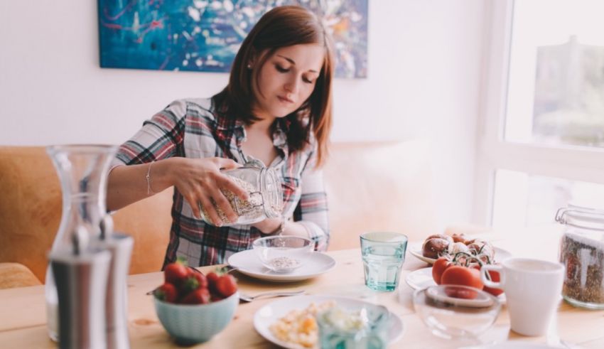 A woman pouring milk into a glass at the breakfast table.