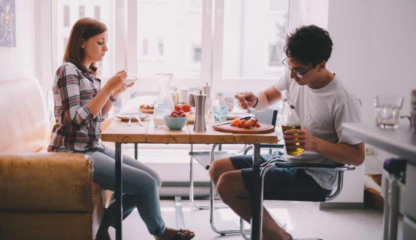 A man and woman sitting at a table eating breakfast.