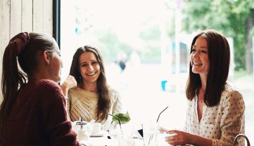 Three women laughing at a table in a restaurant.