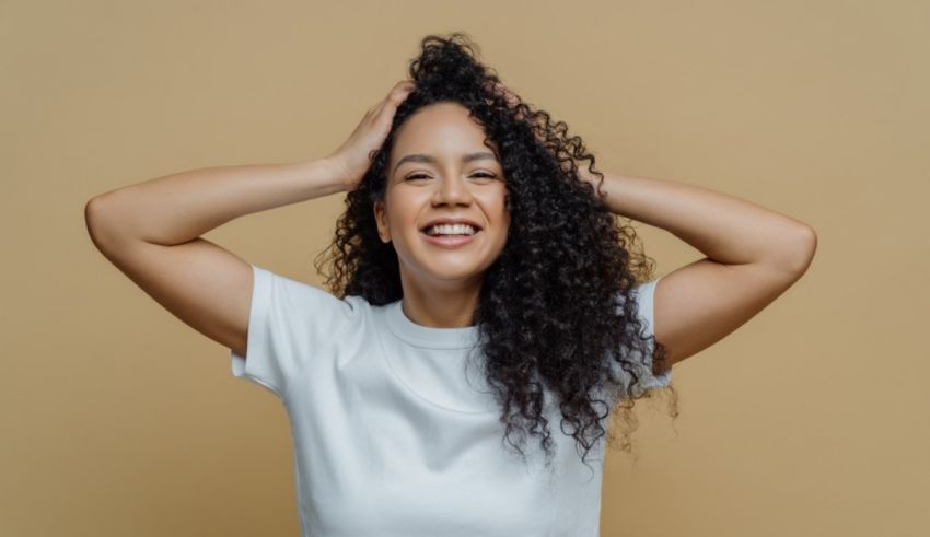 A young woman with curly hair posing on a beige background.